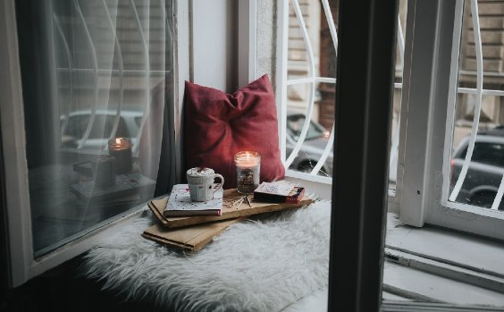 Kerzen und Kissen am Fenster